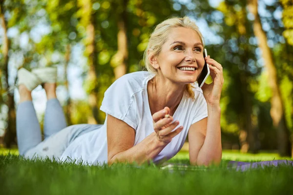 Hermosa mujer alegre hablando en el teléfono móvil en el parque — Foto de Stock