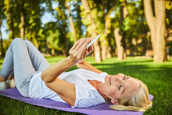 Belle femme joyeuse utilisant un téléphone portable dans le parc — Photo