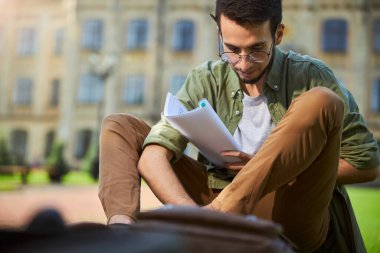 Kulağının arkasında kurşun kalem olan ciddi bir adam dışarıda oturuyor.