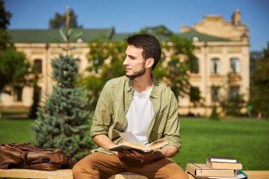 Tahta bir bankta oturan düşünceli öğrenci