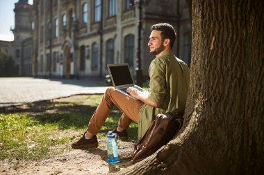 Gülümseyen kısa saçlı üniversite öğrencisi uzaktan bakıyor.