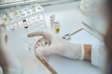 Deneyimli erkek biyokimyacı kan örneği üzerinde çalışıyor.