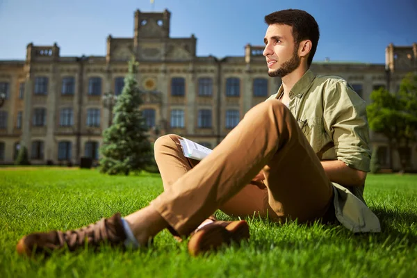 Düşünceli, koyu renk saçlı üniversite öğrencisi uzaktan bakıyor.