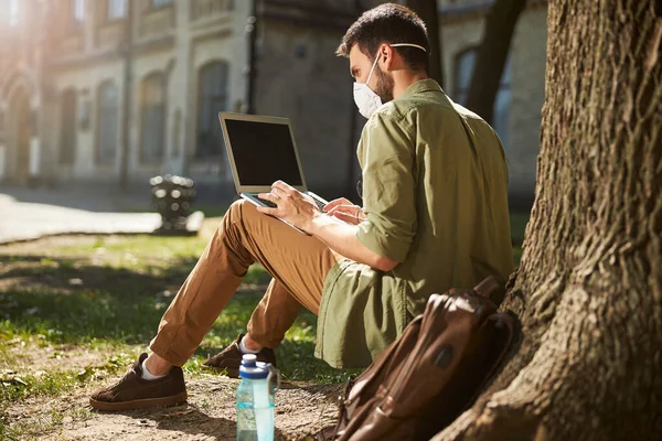 Dizüstü bilgisayarı üzerinde çalışan konsantre erkek öğrenci.