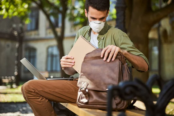 Seriöser Student steckt ein Notizbuch in den Rucksack — Stockfoto