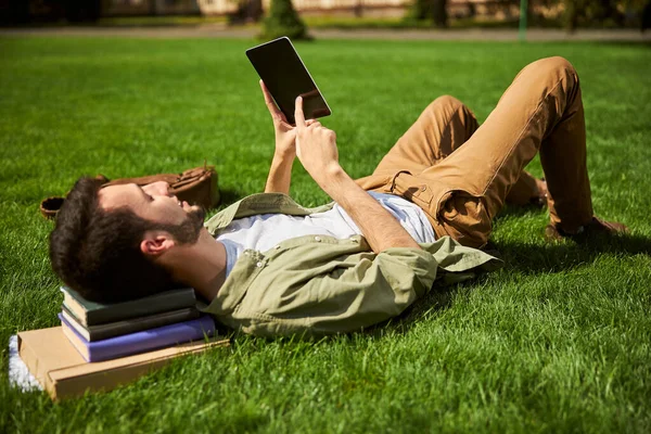 Усміхнений студент коледжу лежить на траві — стокове фото