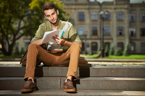 Estudiante universitario enfocado haciendo su tarea afuera — Foto de Stock