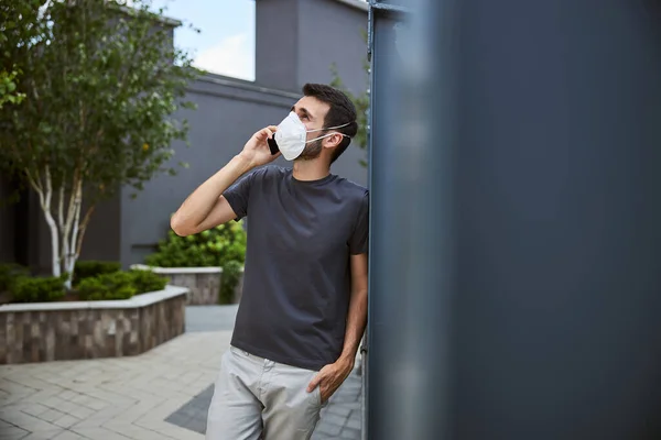 Mann mit Gesichtsmaske ruft das Smartphone an — Stockfoto