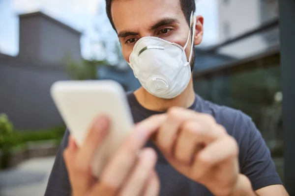 Schwerwiegender junger Mann benutzt sein Handy — Stockfoto