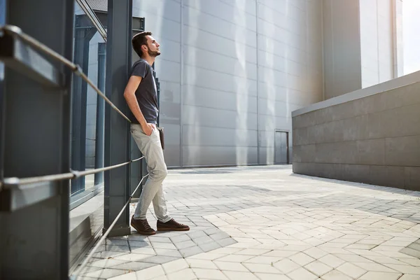 Bir binanın yanında duran düşünceli bir ofis çalışanı.