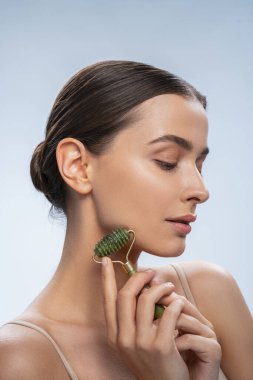 Elinde bir masaj aleti olan güzel bir kadın aşağıya bakıyor.