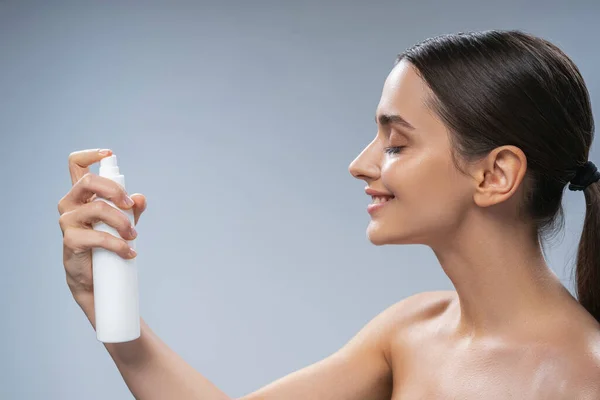 Mujer rociando agua termal sobre su piel — Foto de Stock