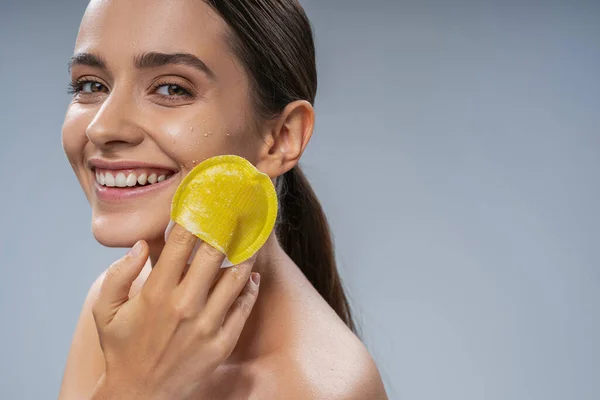 Krásná dáma s zářivým úsměvem exfoliating její pleť — Stock fotografie