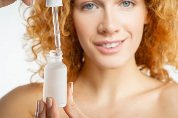 Jeune femme souriante avec une bouteille d'huile — Photo