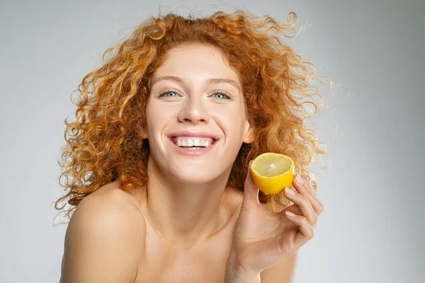 Mujer alegre sosteniendo una mitad de limón en una mano — Foto de Stock