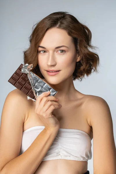 Mujer agradable sosteniendo una barra de chocolate negro —  Fotos de Stock