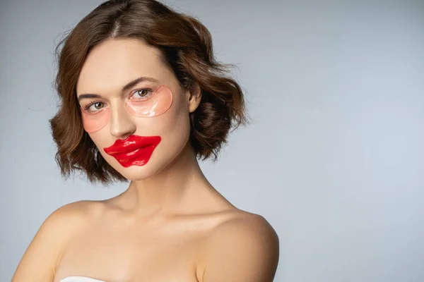 Женщина с коллагеновой маской для губ и гидрогелевыми повязками на глазу — стоковое фото