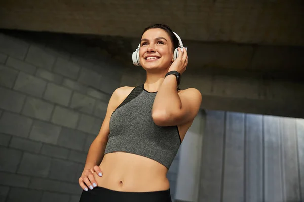 Positiva mujer morena encantada tocando sus auriculares — Foto de Stock