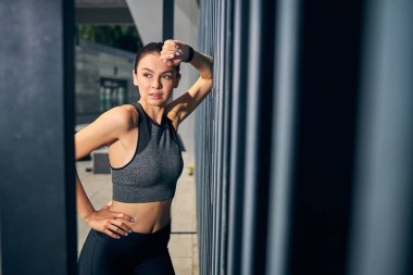 Çekici genç bir kadın duvara yaslanıyor.