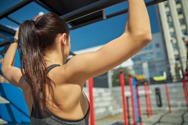 Uzun saçlı esmer, spor malzemelerine bakıyor.