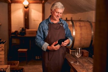 Şarap mahzeninde şarap şişesiyle neşeli bir adam