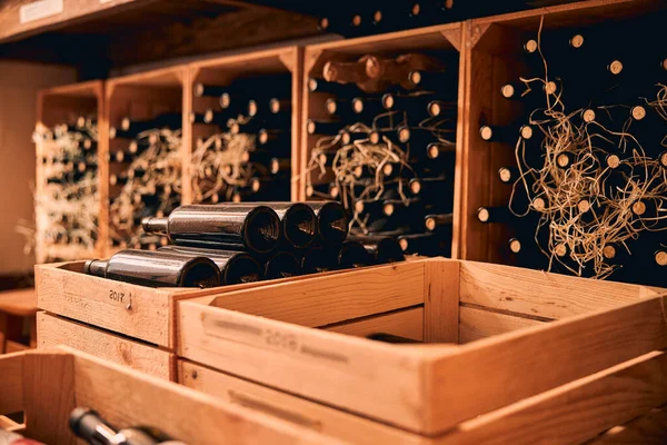 Caixas de madeira com garrafas de vinho de vidro na adega — Fotografia de Stock