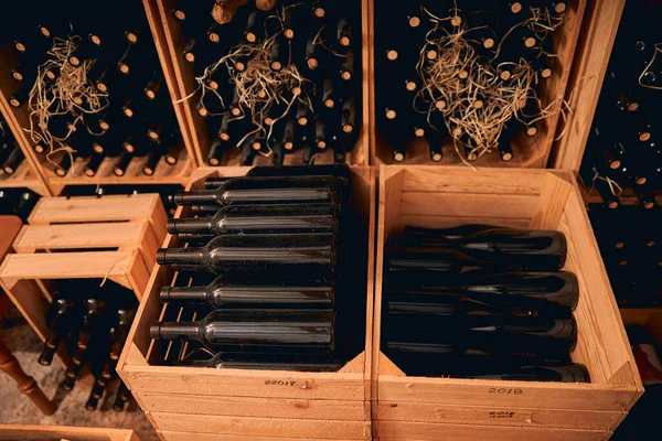 Glasflaskor med vin som förvaras i trälådor och vinhyllor — Stockfoto