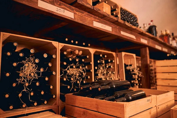 Bottiglie di vetro di vino conservate in casse di legno e portabottiglie — Foto Stock