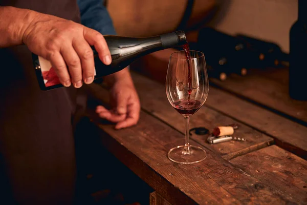Sommelier masculino vertiendo vino tinto en vaso — Foto de Stock