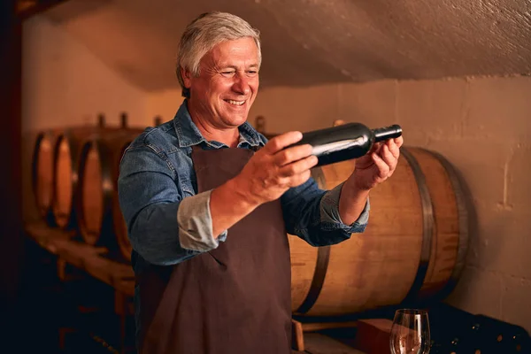 Веселый человек с бутылкой вина, стоящей в винном погребе — стоковое фото