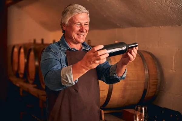 Uomo allegro con bottiglia di vino in piedi in cantina — Foto Stock