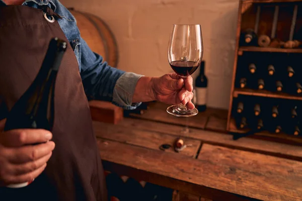 Masculino sommelier segurando garrafa e copo de vinho tinto — Fotografia de Stock