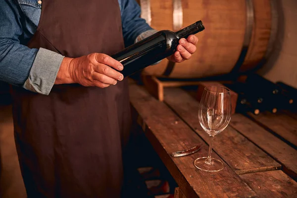 Enólogo masculino em avental segurando garrafa de vinho — Fotografia de Stock