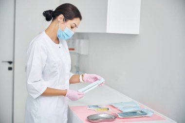 Doktor ellerindeki steril cerrahi aletleri inceliyor.