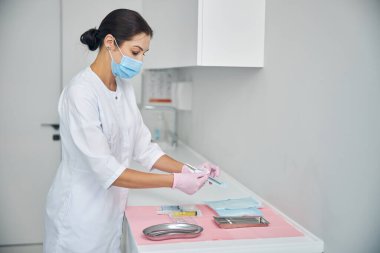 Kadın dermatolog mühürlü biyopsi aletini açıyor.