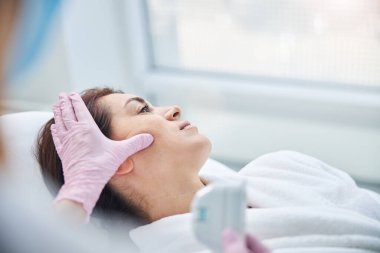 Kozmetik ameliyat sırasında bir kadın başka tarafa bakıyor.