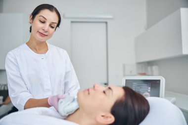 Doktor estetik ameliyat sırasında hastasına bakıyor.