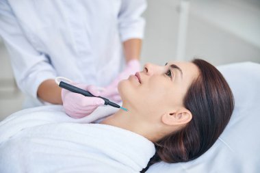 Doktor hastanın derisinde kırmızı bir leke çıkarıyor.