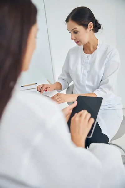 Dermatologist using her gadget during the consultation — Stock Photo, Image