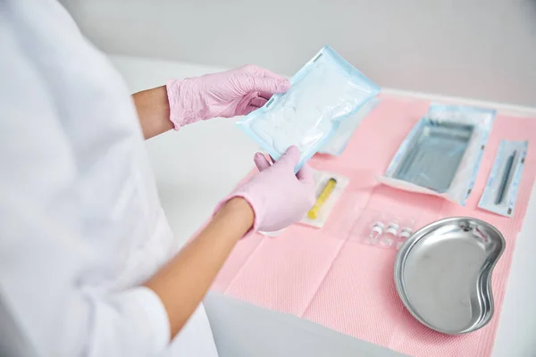 Läkare i latexhandskar undersöker sterila gasbindor — Stockfoto