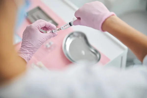 Kosmetikerin in Latexhandschuhen bereitet sich auf eine Spritze vor — Stockfoto