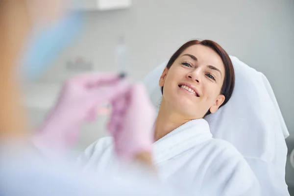Пацієнт у халаті посміхається перед медичною процедурою — стокове фото