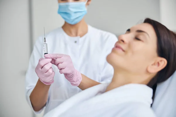 Arzt mit Spritze steht neben einem Patienten — Stockfoto