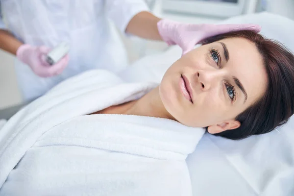 Paciente tranquilo siendo examinado por un dermatólogo con guantes estériles — Foto de Stock