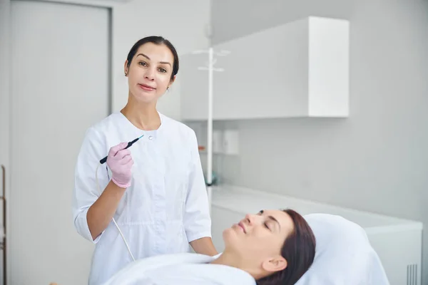 Lugn vänlig hudläkare behandla hennes patient hud — Stockfoto