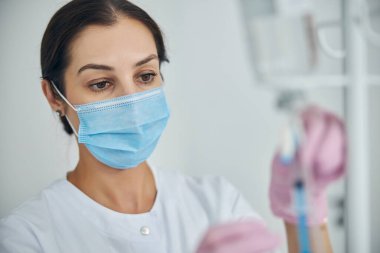 Odaklanmış kadın hemşire tıbbi bir prosedüre hazırlanıyor.