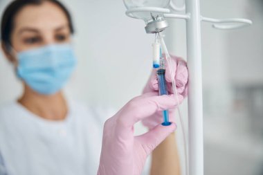 Steril eldivenli kadın damar içi tedaviye hazırlanıyor.