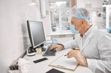Busy healthcare professional looking at a computer screen clipart