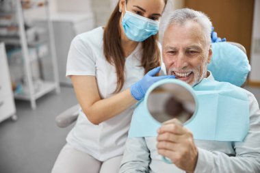 Yaşlı beyefendi yeni diş implantından memnun.