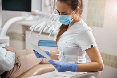 Bir röntgen görüntüsü üzerinde çalışan konsantre kadın diş uzmanı.